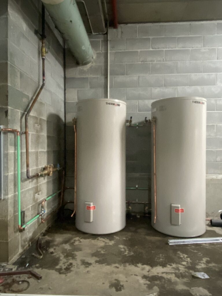 two hot water heaters being replaced in a basement